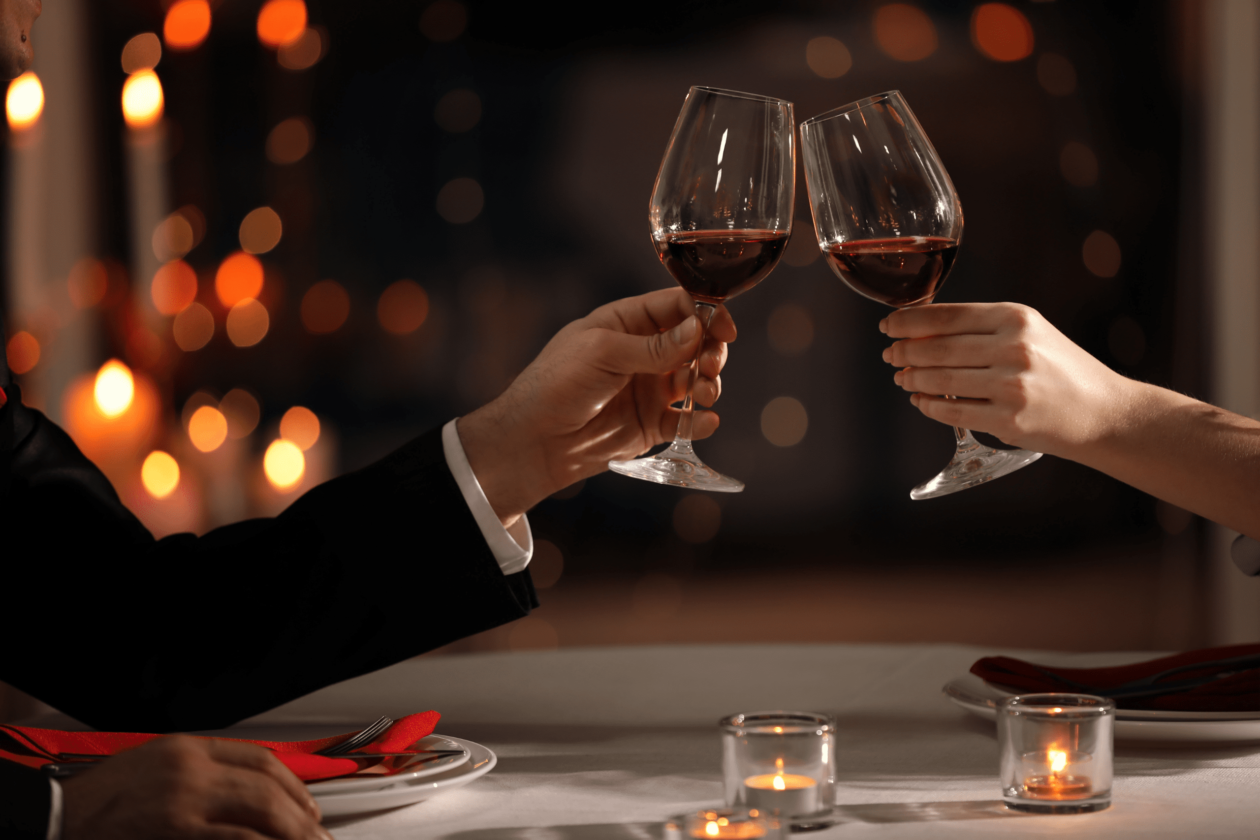 date cheers to wine at a romanic table covered with candles and rose petals