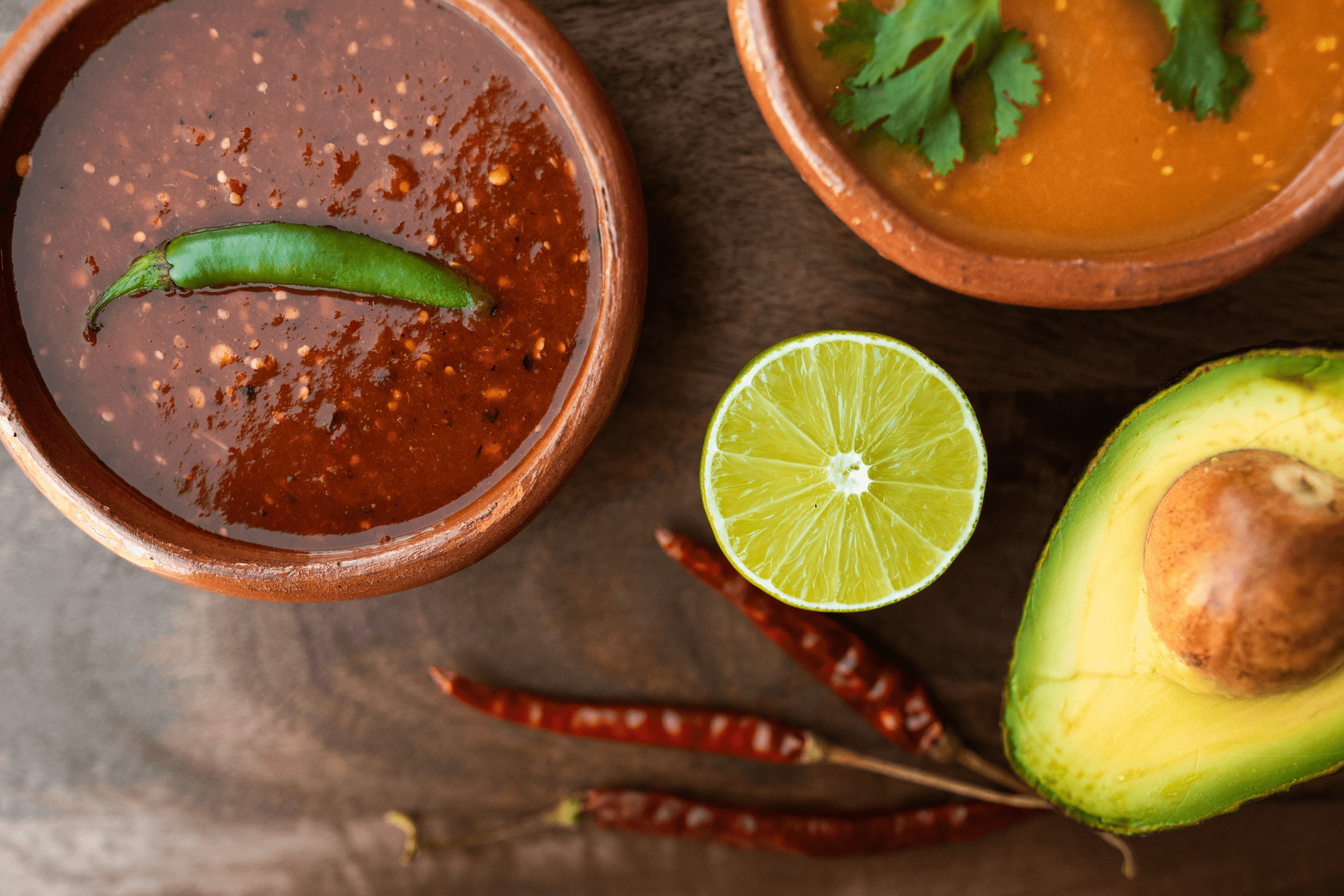 peppers, salsa, avocado, lime, and spicy dip on table